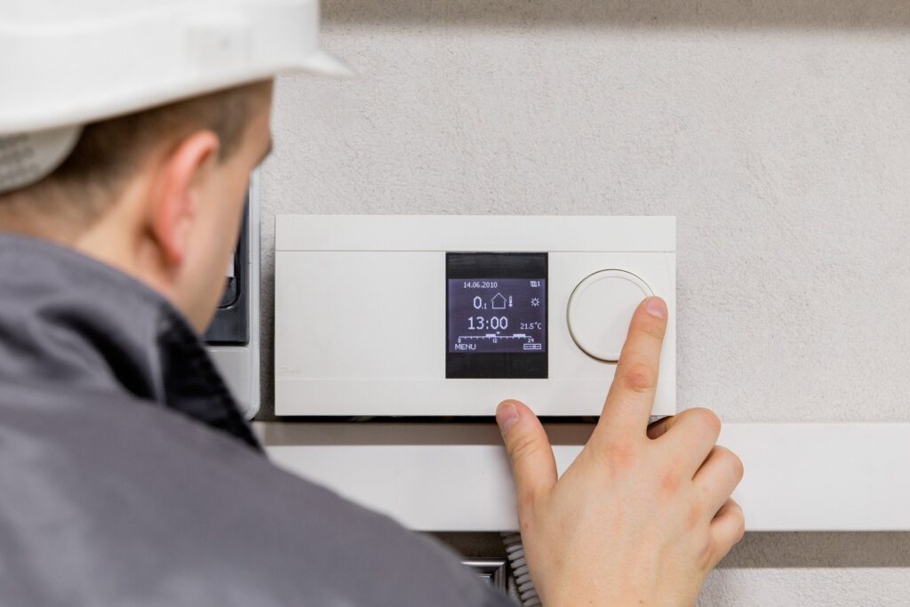 Technician adjusting the newly installed smart thermostat by Clear Air Solutions.